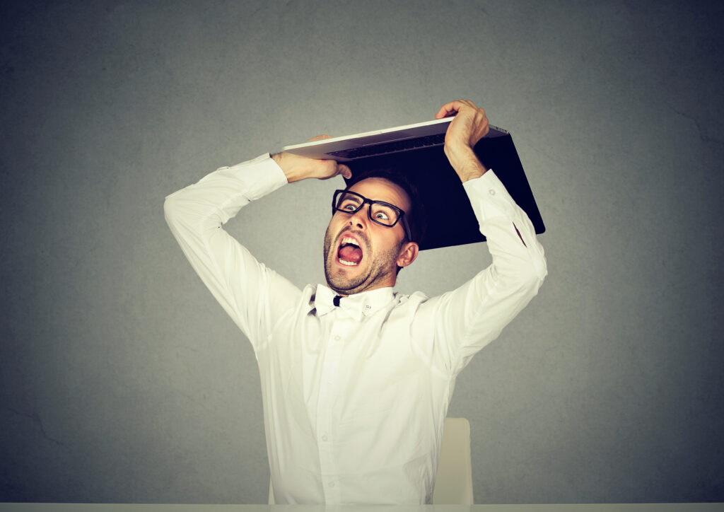 Furious business man about to smash throw his laptop computer.